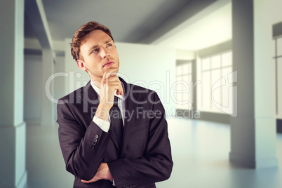 Composite image of young businessman thinking with hand on chin