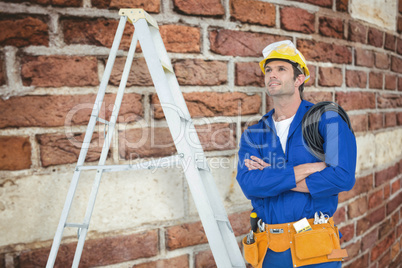 Composite image of thoughtful electrician with arms crossed by l