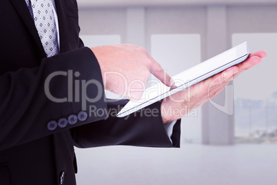 Composite image of businessman using his tablet pc