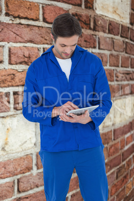 Composite image of mechanic using digital tablet over white back