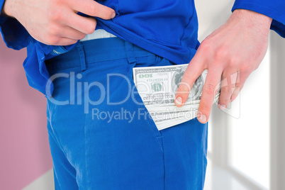 Composite image of handyman putting money in his pocket