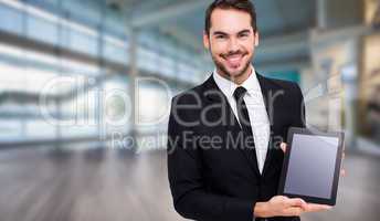 Composite image of smiling businessman showing his tablet pc