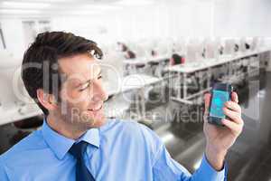 Composite image of smiling businessman showing smartphone to camera
