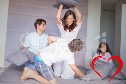 Composite image of family having a pillow fight on the bed