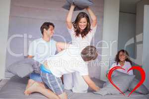 Composite image of family having a pillow fight on the bed