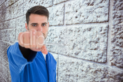 Composite image of confident young male mechanic holding spanner