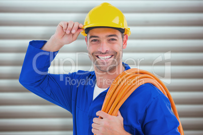 Composite image of confident repairman wearing hard hat while ho
