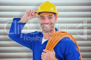Composite image of confident repairman wearing hard hat while ho