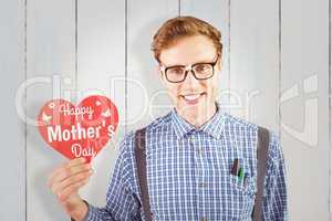 Composite image of geeky hipster holding a heart card