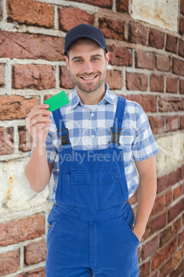 Composite image of smiling young repairman holding green card