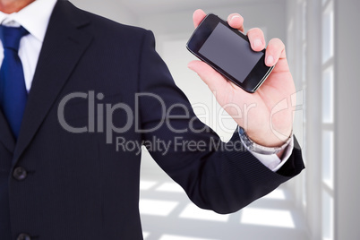 Composite image of mid section of a businessman typing on his ph