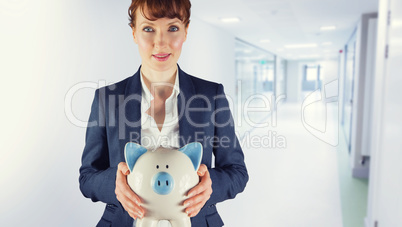 Composite image of businesswoman showing piggy bank