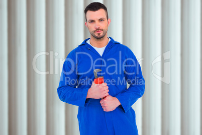 Composite image of smiling male mechanic holding monkey wrench