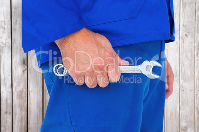 Composite image of mechanic holding spanners on white background