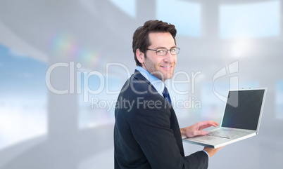 Composite image of smiling businessman using a laptop