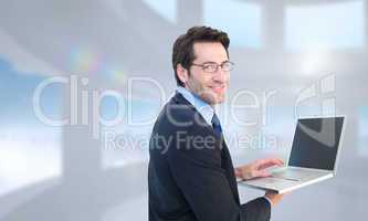 Composite image of smiling businessman using a laptop