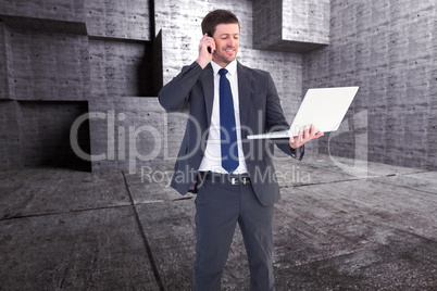 Composite image of businessman talking on phone holding laptop