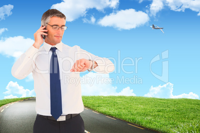 Composite image of businessman on the phone looking at his wrist