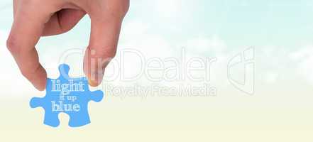 Composite image of hand holding jigsaw piece