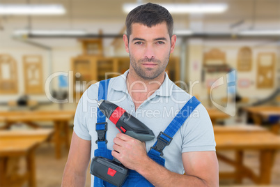 Composite image of portrait of confident carpenter holding power