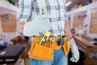 Composite image of technician with tool belt around waist holdin