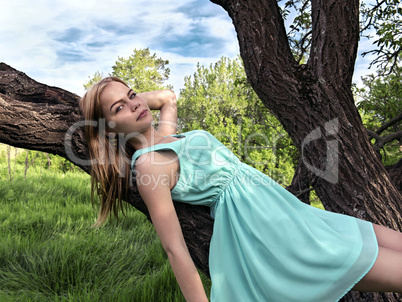 Young sensual blonde girl lying on a tree branch