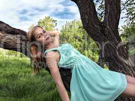 Young sensual blonde girl lying on a tree branch