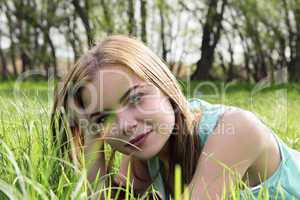 Young sensual smiling blonde lying on the grass in the sunlight