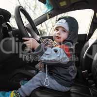 little boy sitting behind the wheel of a car