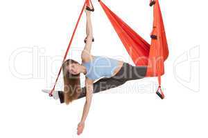 Young woman doing anti-gravity aerial yoga in hammock on a seamless white background.