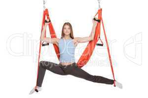 Young woman doing anti-gravity aerial yoga in hammock on a seamless white background.