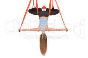 Young woman doing anti-gravity aerial yoga in hammock on a seamless white background.