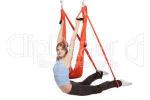 Young woman doing anti-gravity aerial yoga in  red hammock on a seamless white background.