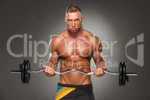 Portrait of super fit muscular young man working out in gym.