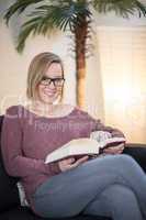 Junge Frau im Wohnzimmer liest ein Buch