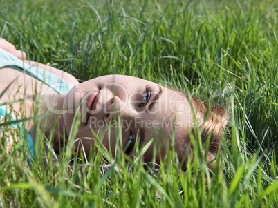 Young sensual smiling blonde lying on the grass in the sunlight