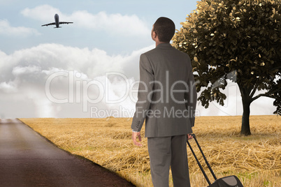 Composite image of young businessman standing with suitcase