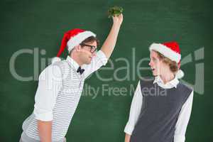Composite image of geeky hipster holding mistletoe