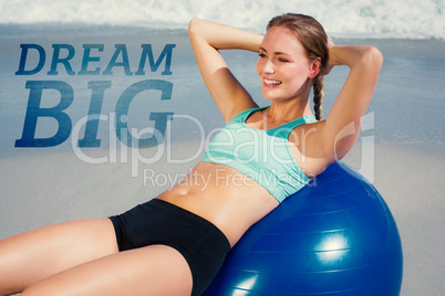 Composite image of fit woman lying on exercise ball at the beach