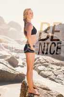 Composite image of fit blonde standing on the beach on a rock