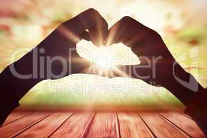 Composite image of woman making heart shape with hands