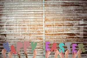 Composite image of hands holding up happy easter