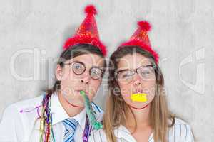 Composite image of geeky hipster wearing a party hat with blowin
