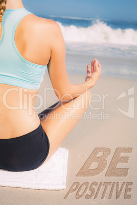 Composite image of fit woman sitting on the beach in lotus pose