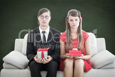 Composite image of unsmiling geeky couple with gift