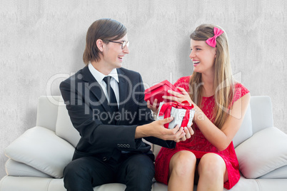 Composite image of cute geeky couple smiling and offering gift