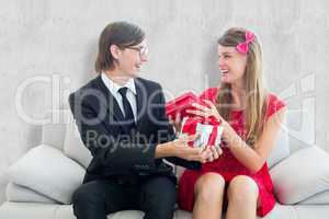 Composite image of cute geeky couple smiling and offering gift