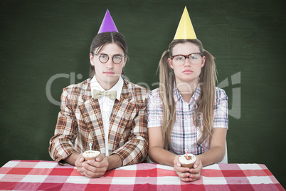 Composite image of unsmiling geeky hipsters celebrating birthday