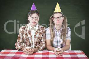 Composite image of unsmiling geeky hipsters celebrating birthday