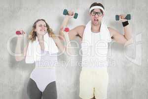 Composite image of geeky hipster couple lifting dumbbells in spo